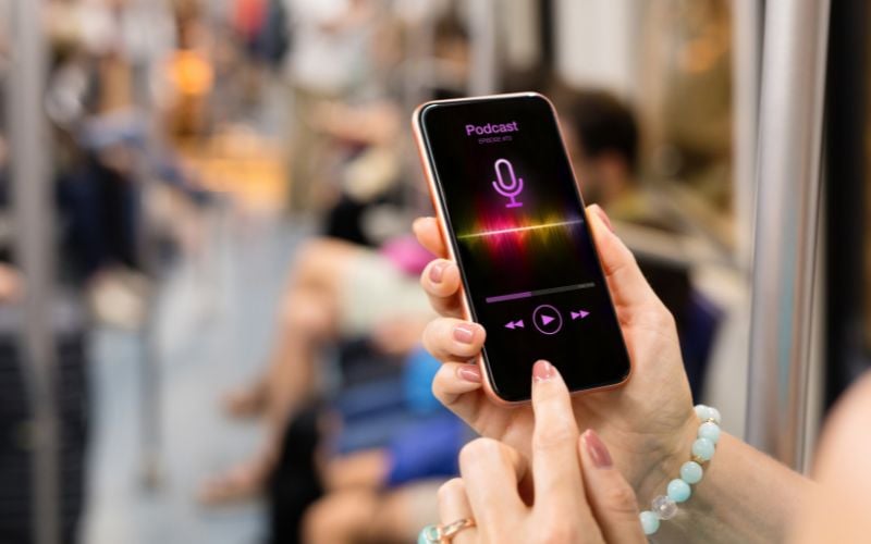 Woman's hands with a bracelet accessing a podcast on a smartphone