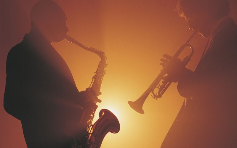 Two jazz musicians playing on stage with an orange light in the background