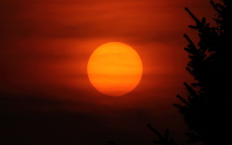 The sun in a hazy orange sky at dusk